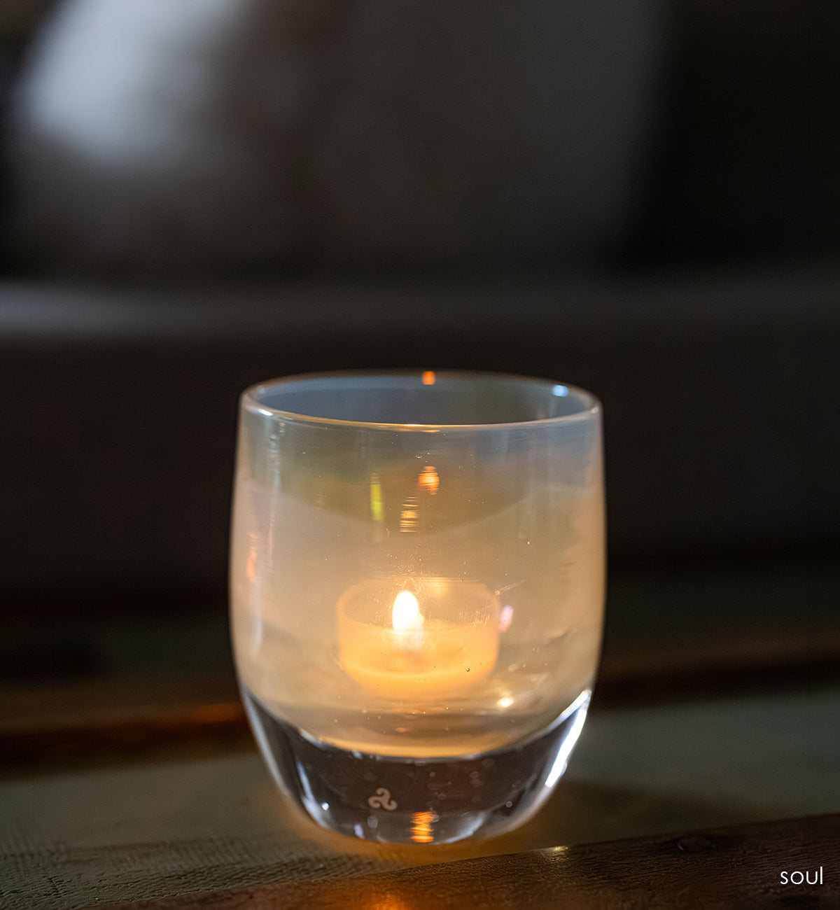 'sou' a light yellow transparent glass candle holder with a lit candle on a dark background