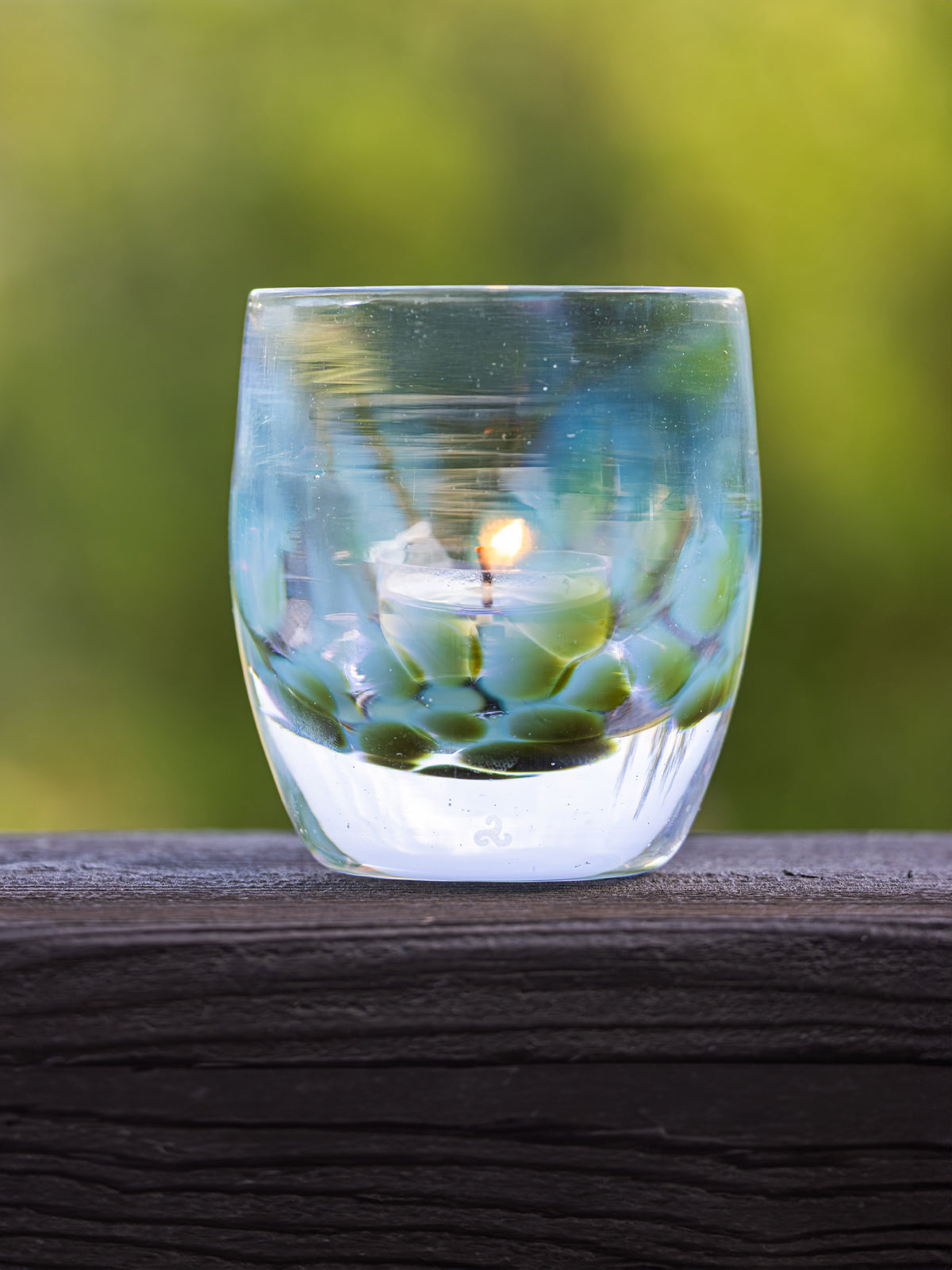 spirited away glassybaby transparent blue and green glass votive candle holder on wooden railing