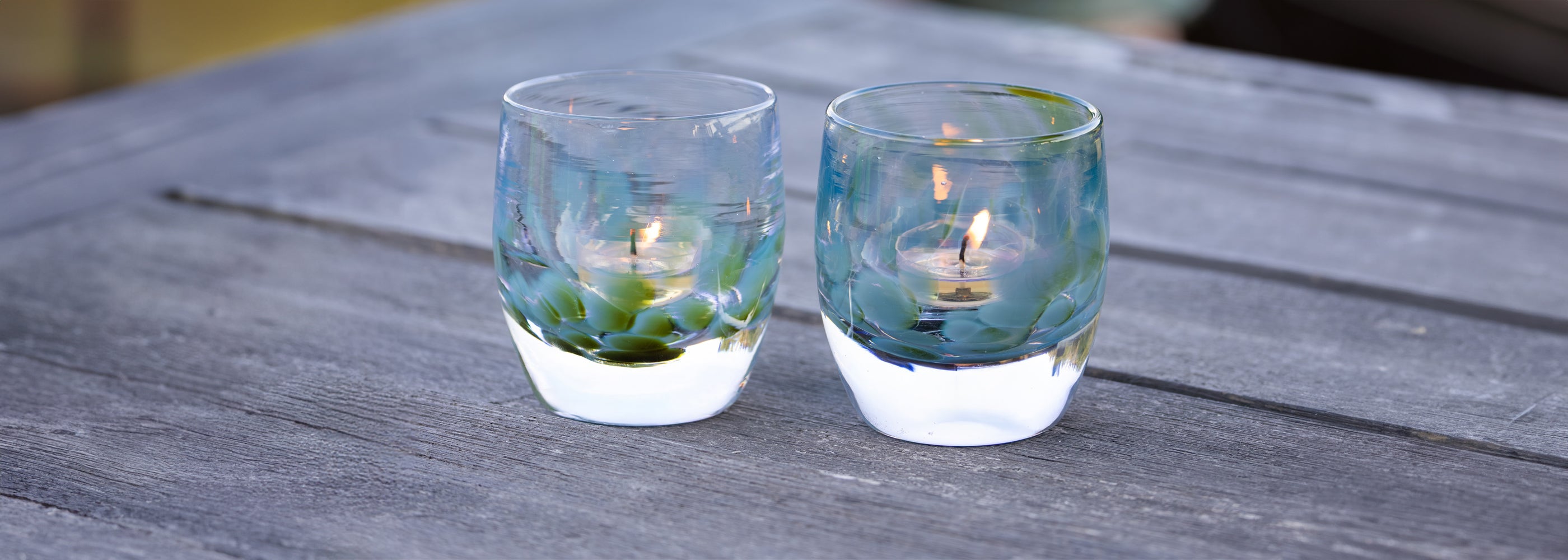 spirited away glassybaby transparent blue and green glass votive candle holder on gray table