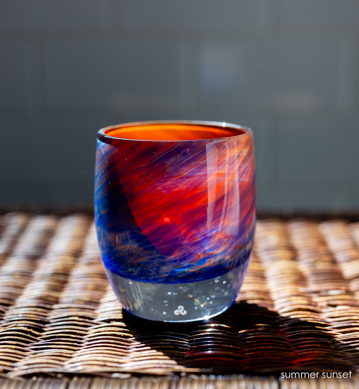 'summer sunset' glassybaby | red, yellow, and blue hand-blown glass candle holder on wicker table