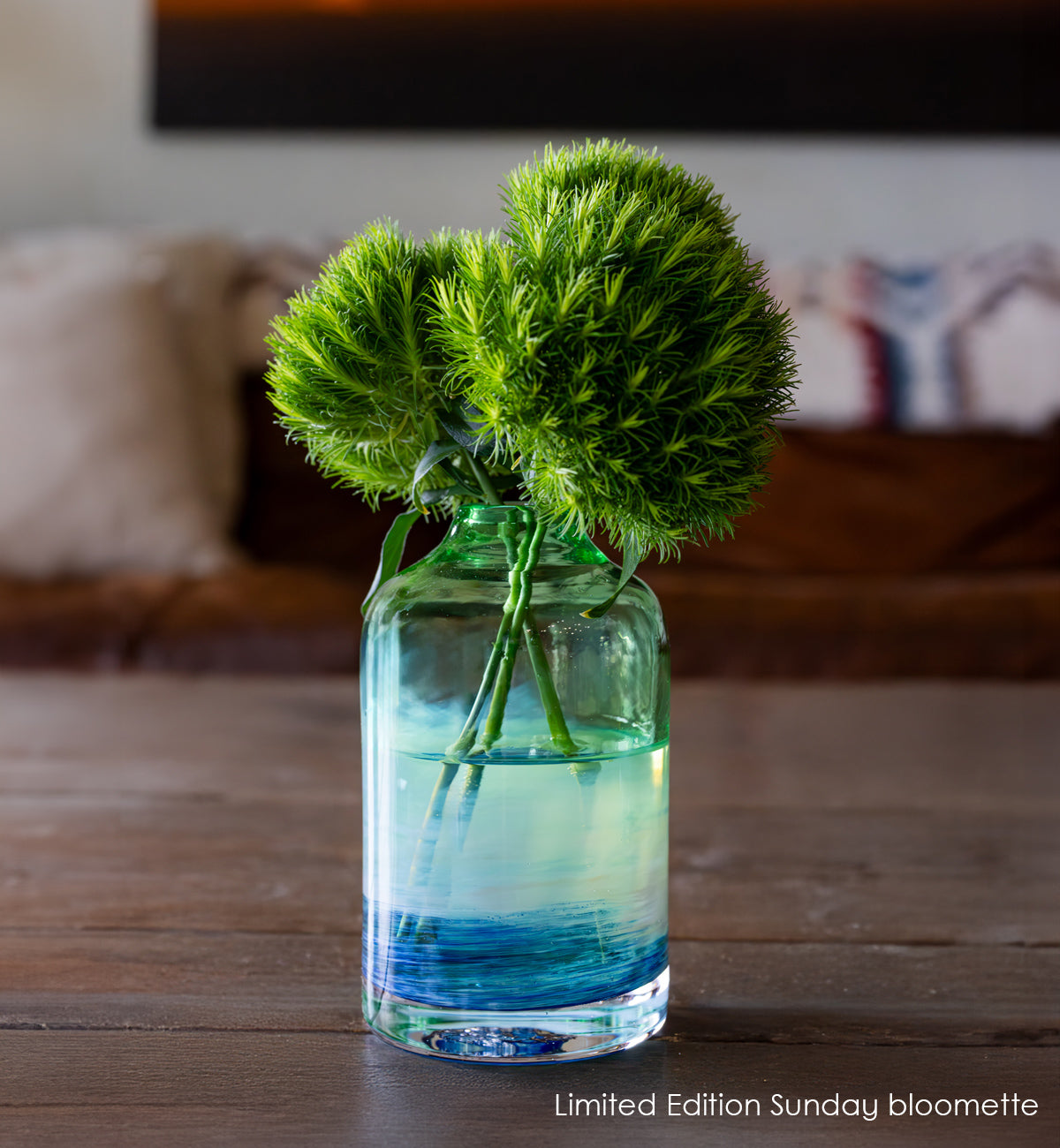 glassybaby bloomette transparent glass vase with blue and white accents on a wooden table with flowers inside the vase