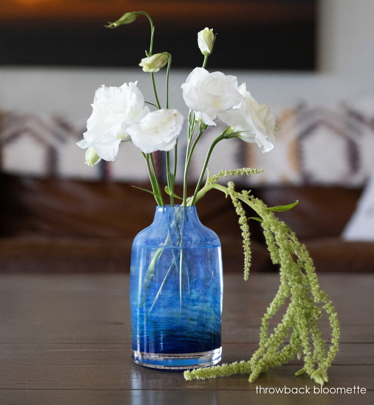 glassybaby seahawk bloomette transparent glass vase blue swirls with white and green flowers on a wooden table