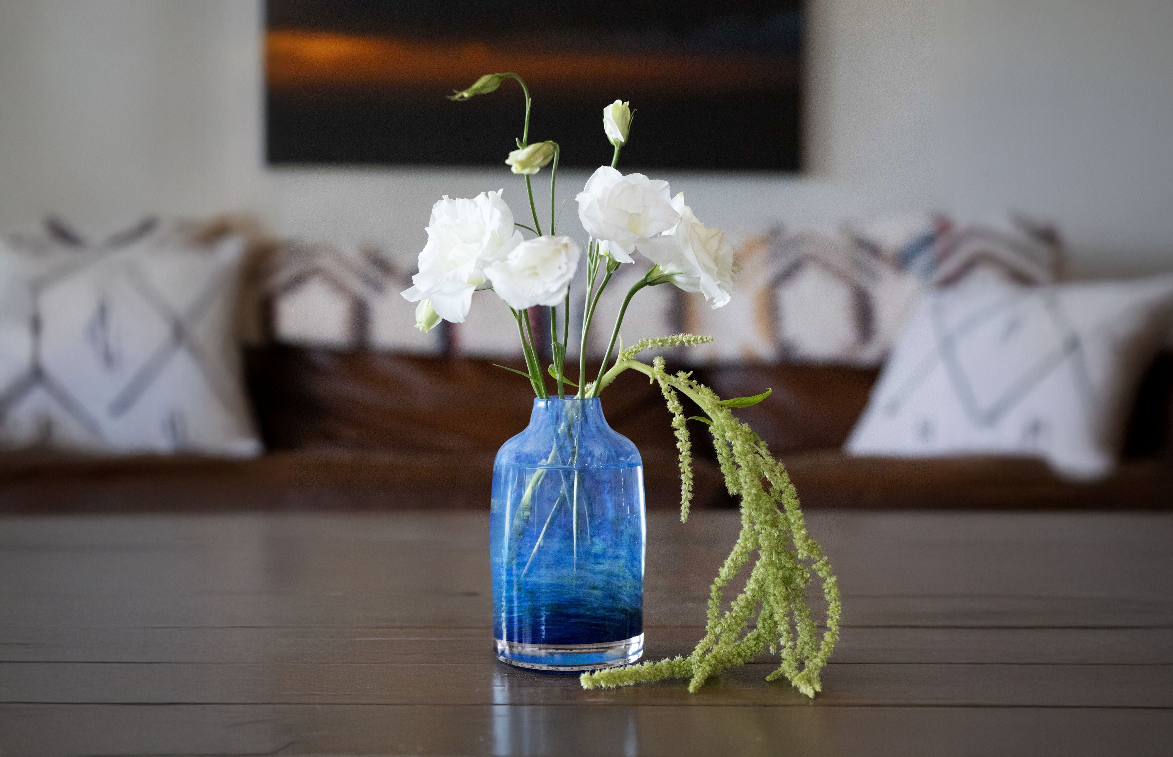 glassybaby seahawk bloomette transparent glass vase blue swirls with white and green flowers on a wooden table