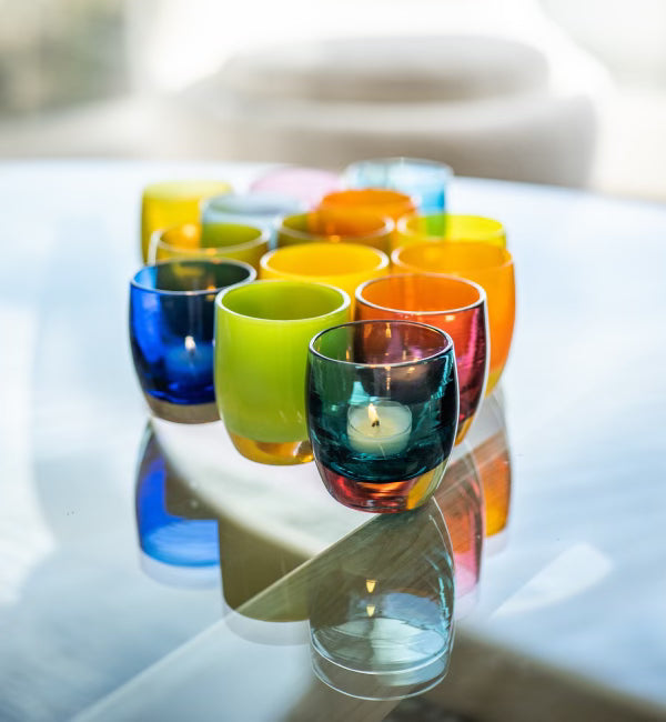 transparent hand-blown glass votive candle holders on a glass coffee table.