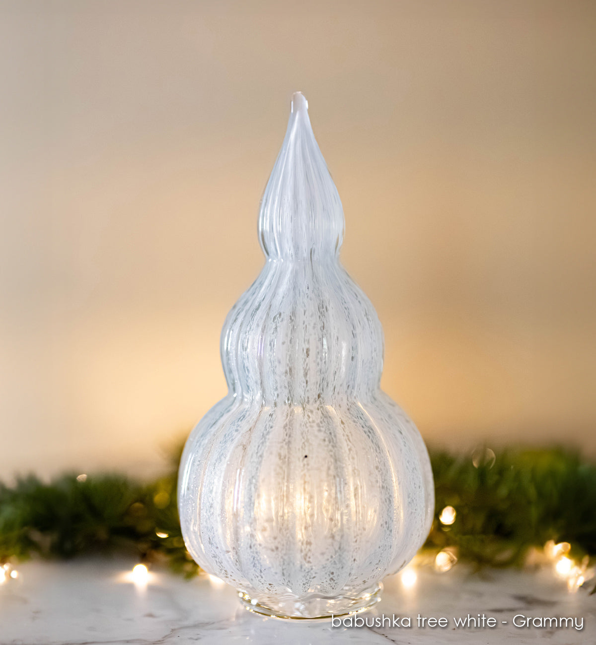Grammy babushka tree white, with lights and garland in background.