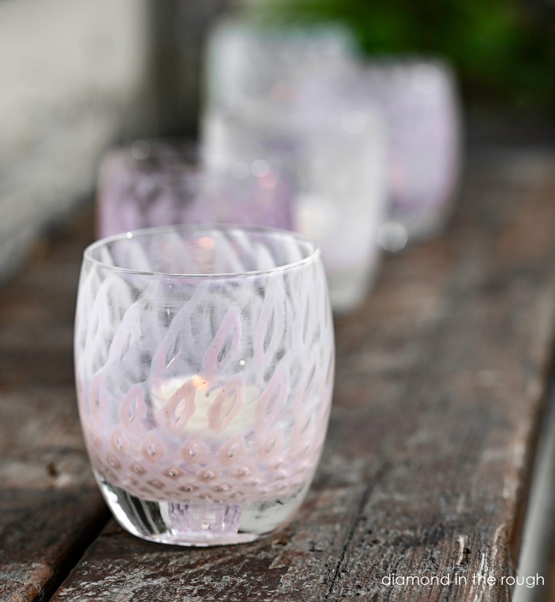 diamond in the rough, light pink bubble, hand-blown glass votive candle holder on a wood bench, with yes and diamond in the rough blurred in background.
