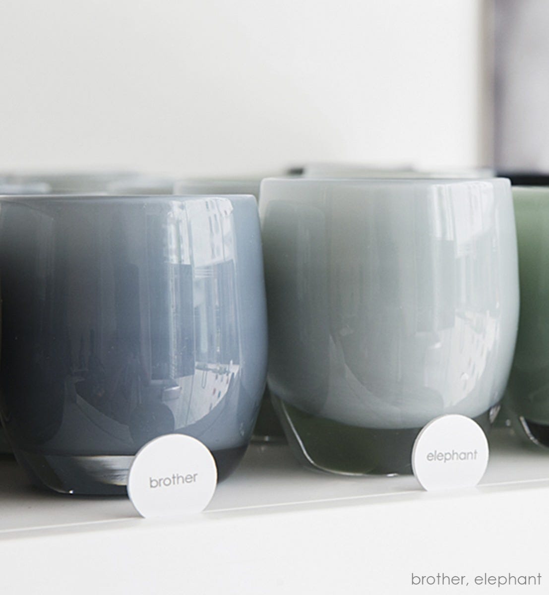 elephant shaded gray hand-blown glass votive candle holder next to brother on a glassybaby shelf.