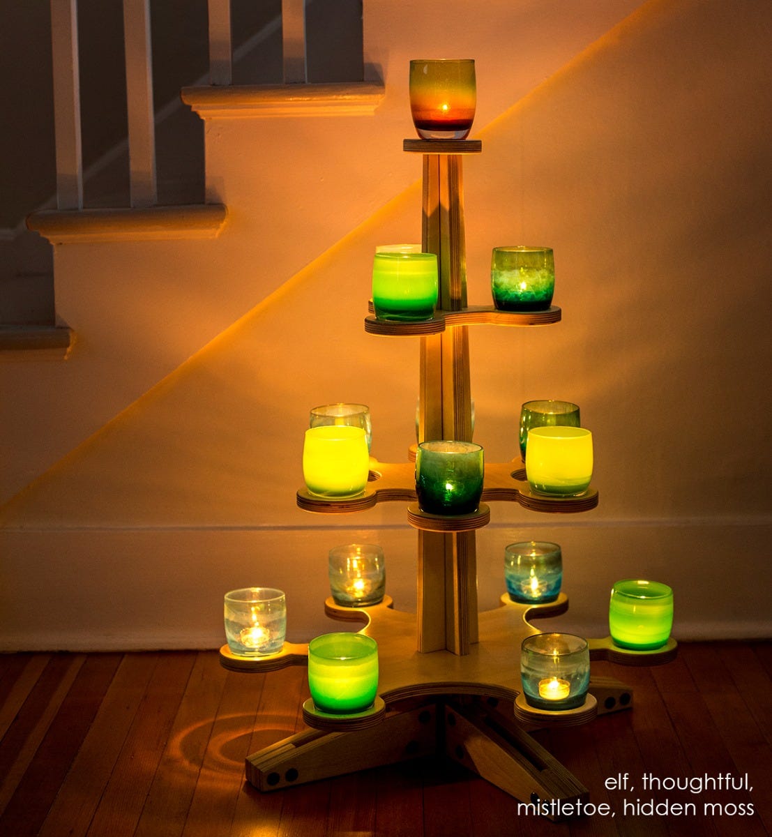 elf opaque light green hand-blown glass votive candle holder. Paired with thoughtful, mistletoe, and hidden moss on a wood glassybaby tree in front of a staircase.
