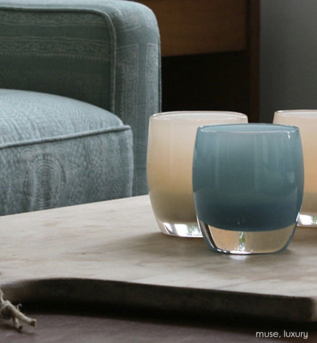 luxury turkish blue hand-blown glass votive candle holder with muse on a wood tray on leather living room ottoman.