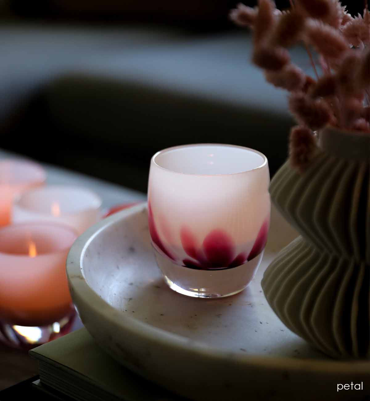 petal, white with pink petals emerging from the bottom, hand-blown glass votive candle holder in a ceramic platter with a vase.