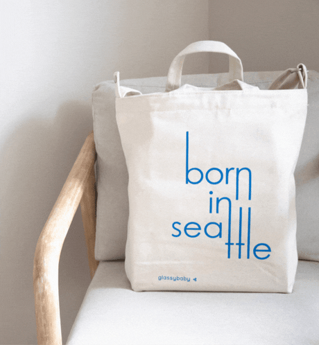 blue bear holding glassybaby, "crafted in seattle" canvas tote on a white and light wood chair.