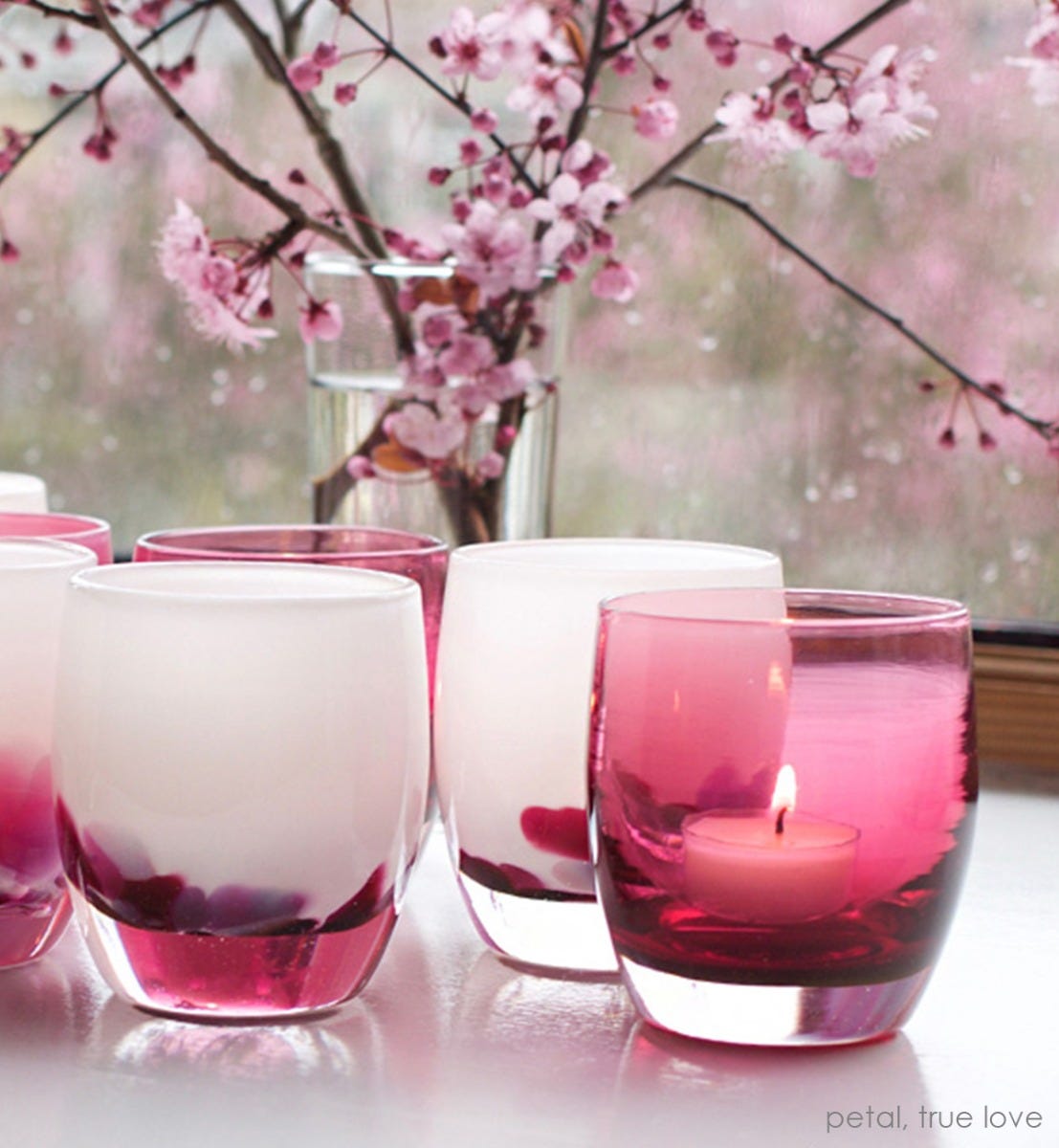 true love, transparent deep raspberry pink, hand-blown glass votive candle holder. Paired with petal on a white table with flowers in background.