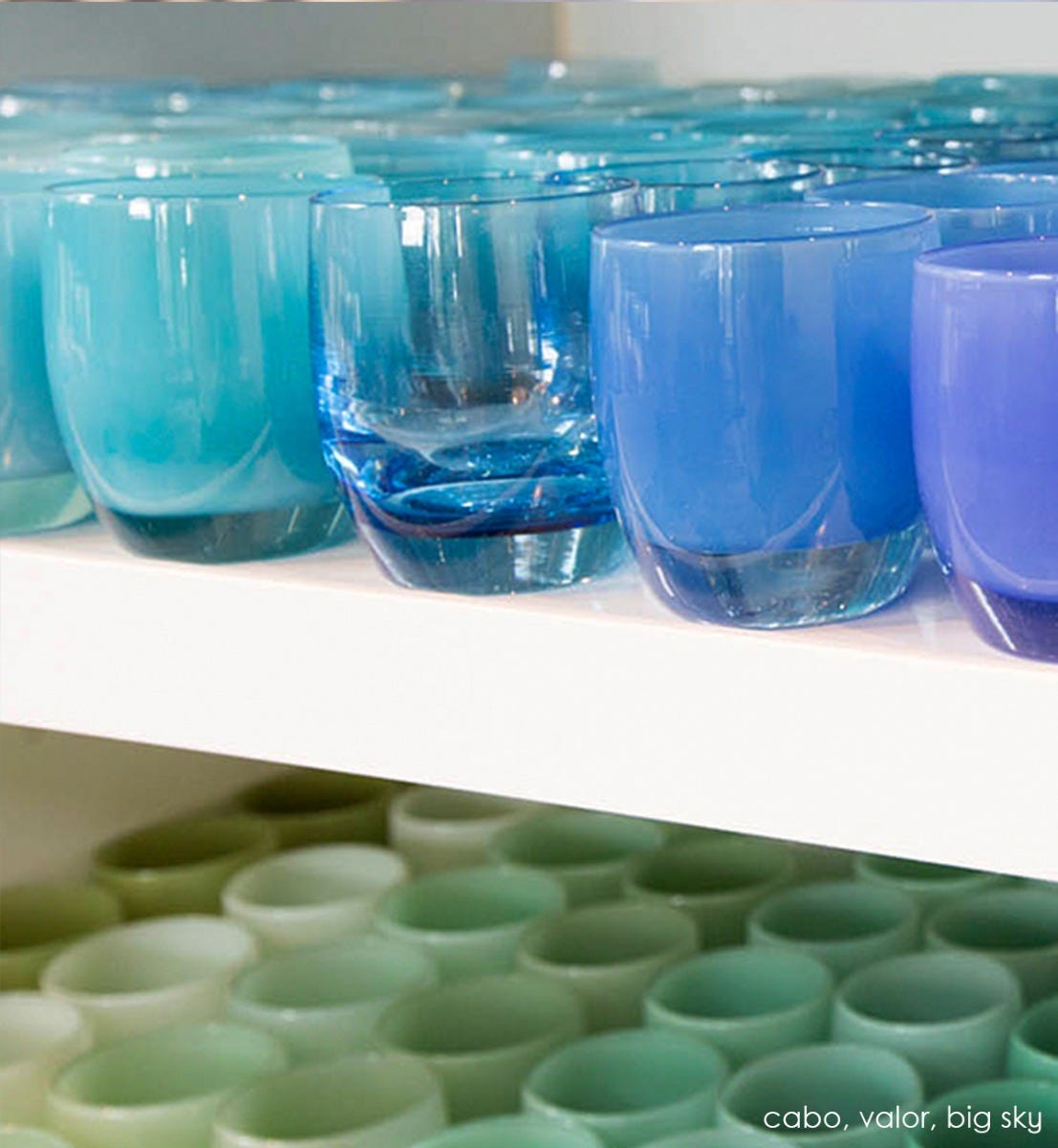 valor clear light blue hand-blown glass votive candle holder next to cabo and big sky on a glassybaby shelf.