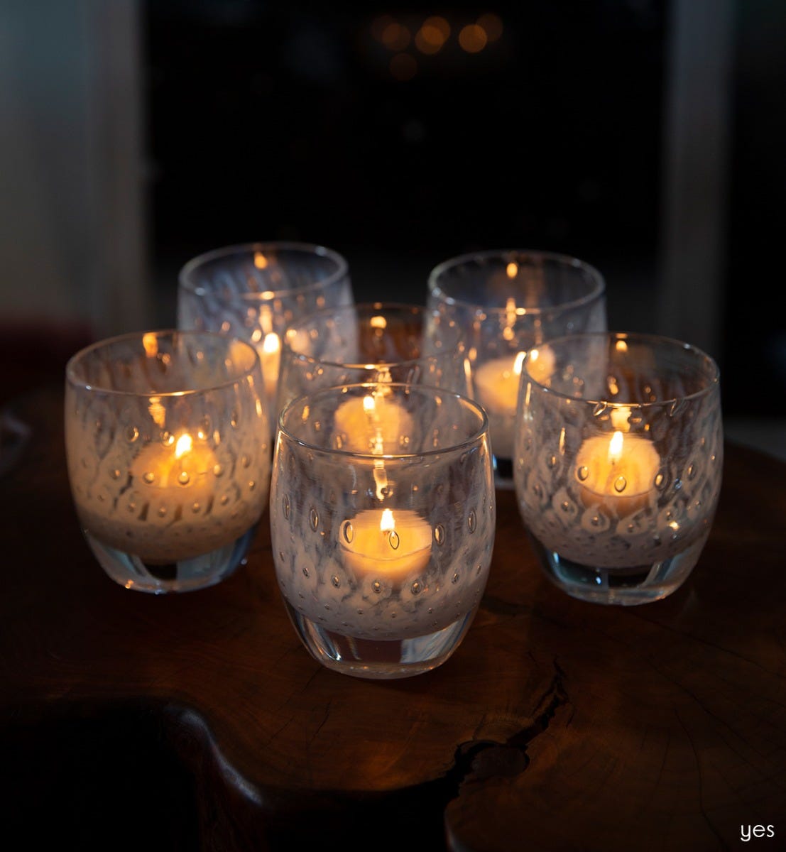 grouping of yes, white unique bubble pattern hand-blown glass votive candle holders in a dark living room.