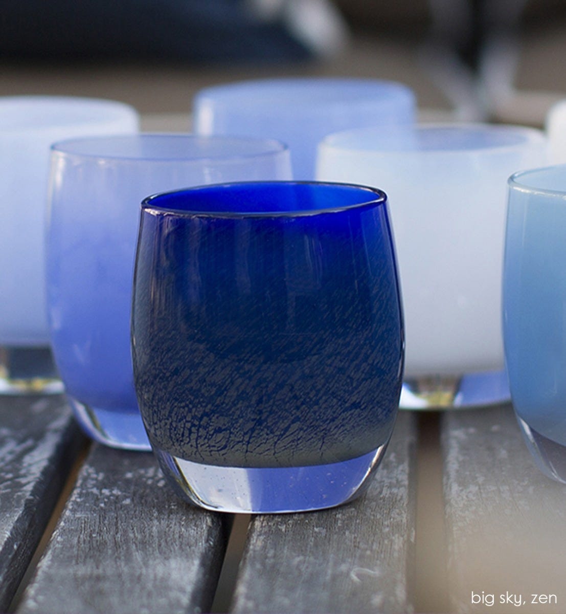 zen, midnight blue textured, hand-blown glass votive candle holder in a group with big sky on wood picnic table.