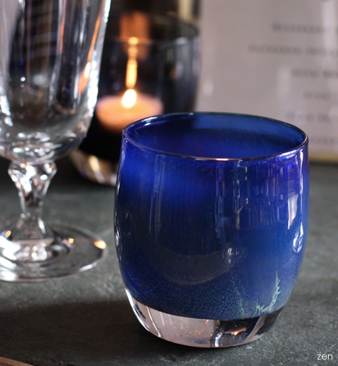 zen, midnight blue textured, hand-blown glass votive candle holder on a wedding table with a wine glass and menu.